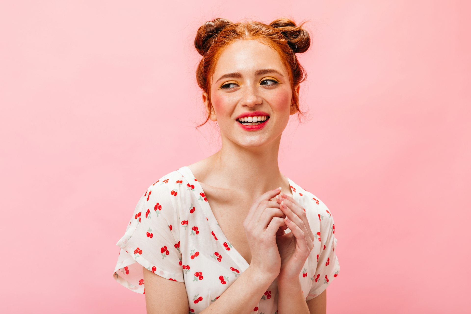 a woman in a white dress smiling and holding her hands together